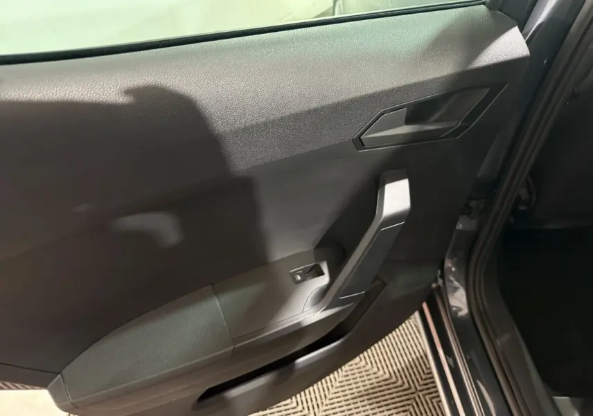 Vue intérieure côté gauche de la porte arrière grise foncée de la SEAT IBIZA 2024 avec poignée et commande de lève-vitre.