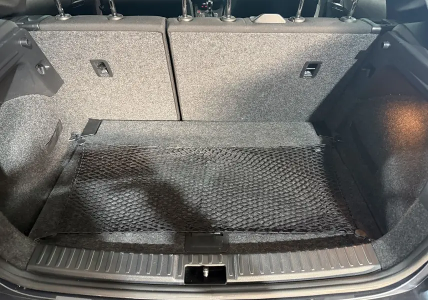 Vue du coffre ouvert de la SEAT Ibiza 1.0 TSI 110 FR gris foncé, montrant la banquette arrière et un filet de rangement.