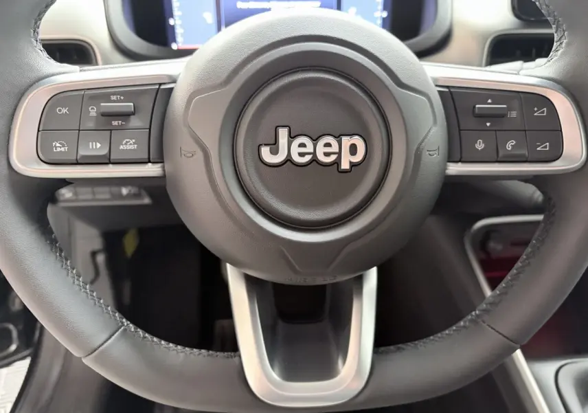 Gros plan sur le volant cuir noir du Jeep Avenger 2025 avec commandes multifonctions et logo central Jeep.