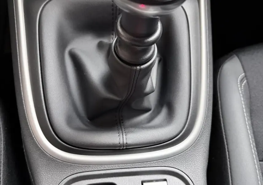 Gros plan sur la commande de boîte manuelle et les boutons de frein à main électrique et mode de conduite dans un Jeep Avenger noir.