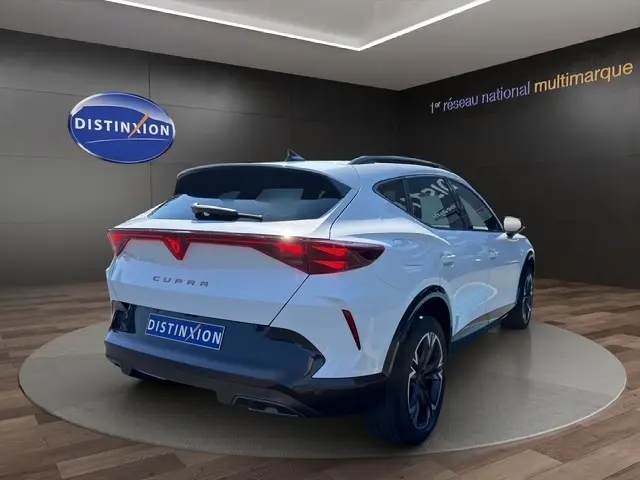 Vue 3/4 arrière d’un CUPRA Formentor blanc 2025 avec feux arrière LED et jantes noires, en showroom.