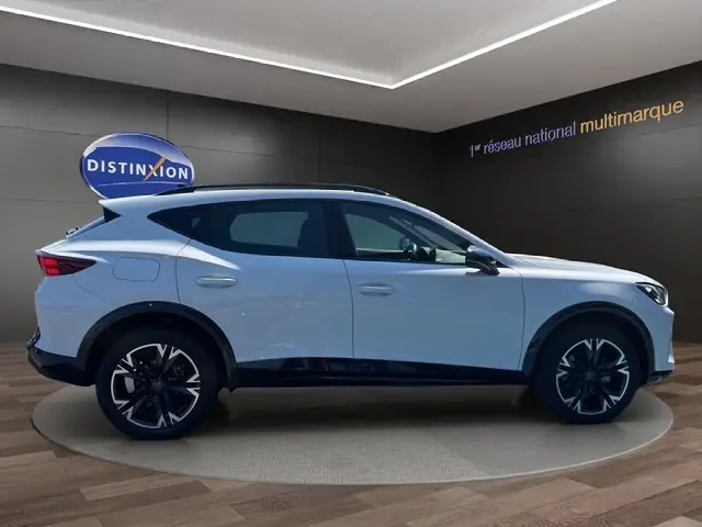 Vue latérale droite d'un CUPRA Formentor blanc 2025 en intérieur, soulignant ses jantes noires et design sportif.