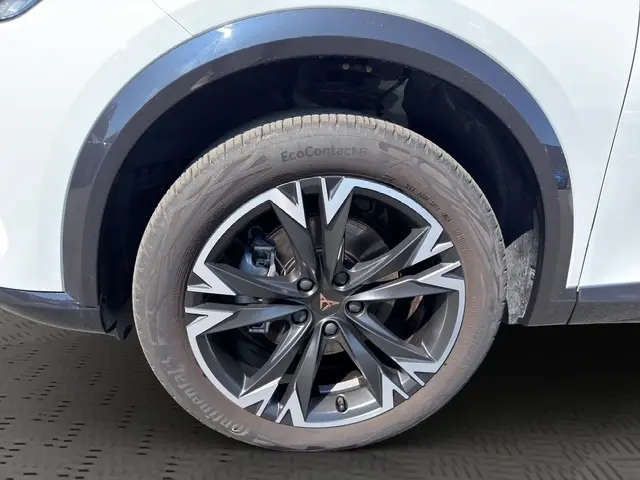 Gros plan sur la roue avant droite d’un CUPRA Formentor blanc, mettant en valeur la jante en alliage noir et argent au design anguleux.