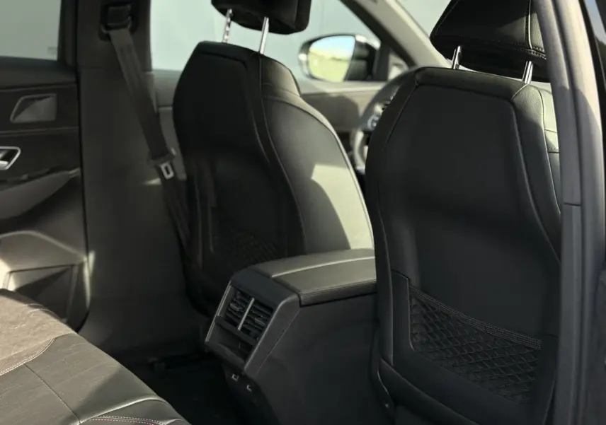 Vue arrière intérieure du DS7 2025 noir Perla montrant les sièges avant en cuir et la console centrale avec aérateurs arrière.