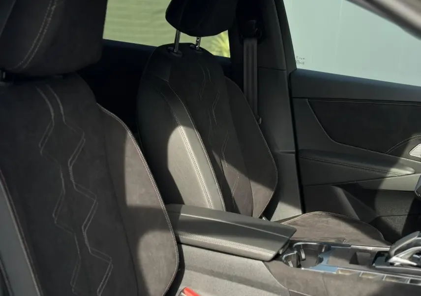 Vue intérieure des sièges avant en Alcantara noir profond avec surpiqûres Carmin et Or du DS7 2025.