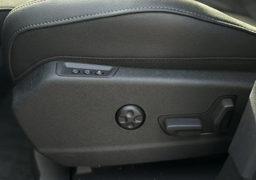 Gros plan sur les commandes électriques de réglage lombaire du siège avant en cuir noir du DS7 2025.