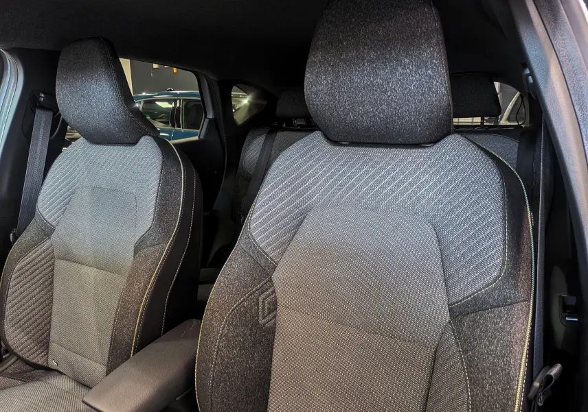 Gros plan sur les sièges avant en tissu gris foncé du Renault Captur Mild Hybrid 160 CH EDC TECHNO 2025.