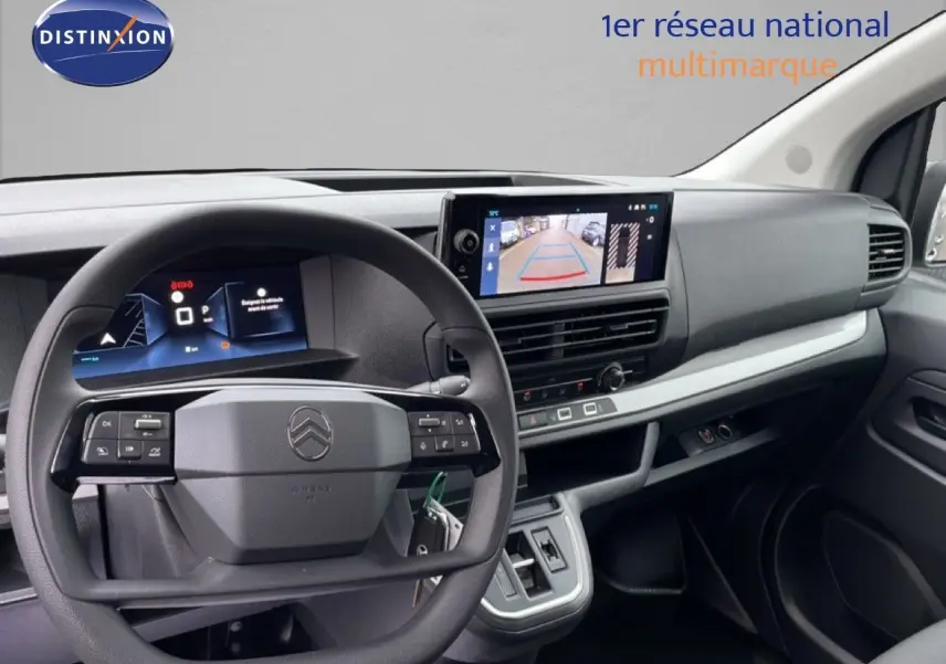 Vue intérieure du tableau de bord et volant du Citroën Jumpy gris, avec écran central affichant la caméra de recul.