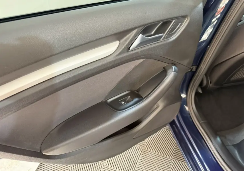 Vue rapprochée de la porte arrière droite bleu foncé d’une Audi A3 2.0 TDI 2018 avec poignée et commande de lève-vitre.
