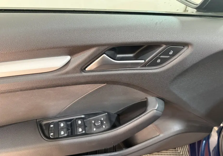 Gros plan sur la porte avant gauche bleu foncé d’une Audi A3 2.0 TDI 2018 avec commandes de vitres et verrouillage.