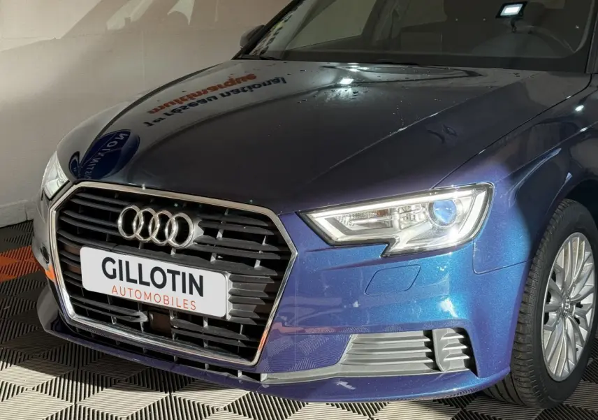 Vue 3/4 avant droit d'une Audi A3 2.0 TDI Business Line bleu métallisé avec phares LED et calandre chromée.