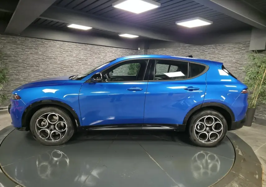 Vue latérale droite d'un Alfa Romeo Tonale bleu métallisé avec jantes alliage 18 pouces et détails noirs brillants.