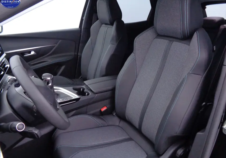 Vue intérieure côté conducteur du Peugeot 3008 2023, sièges en tissu gris et cuir noir avec surpiqûres bleues.