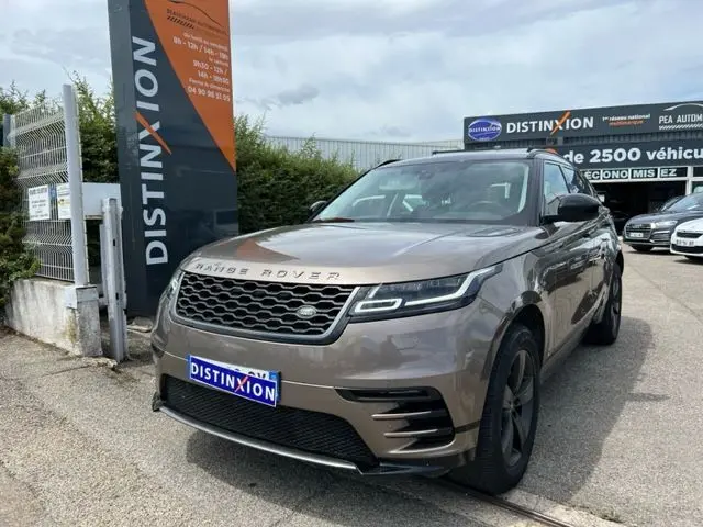 Range Rover Velar marron 3/4 avant droit, mettant en valeur sa calandre distinctive et ses phares LED fins.