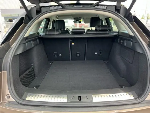 Coffre ouvert d'un Range Rover Velar marron 2018, vue arrière montrant l'espace de chargement et les sièges noirs.