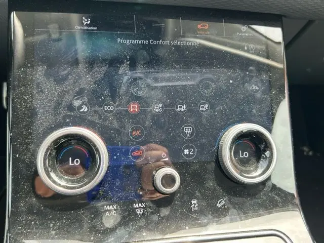 Gros plan sur la console centrale du Range Rover Velar marron 2018, affichant le réglage du programme Confort et la climatisation.