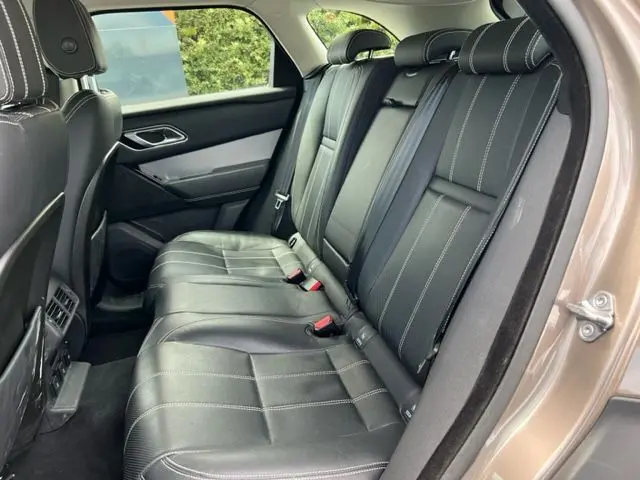 Vue intérieure côté droit du Range Rover Velar marron 2018, sièges arrière en cuir noir avec surpiqûres blanches.