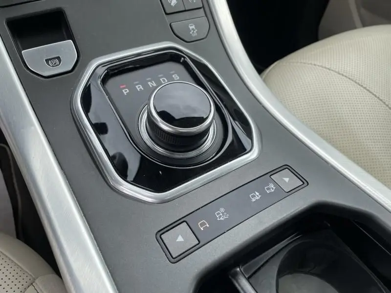 Vue rapprochée de la molette de sélection de vitesse et des commandes de terrain du Range Rover Evoque marron métal, intérieur beige.
