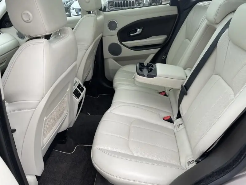 Vue intérieure arrière côté droit du Range Rover Evoque 2017, sièges cuir beige clair avec accoudoir central et porte noir.