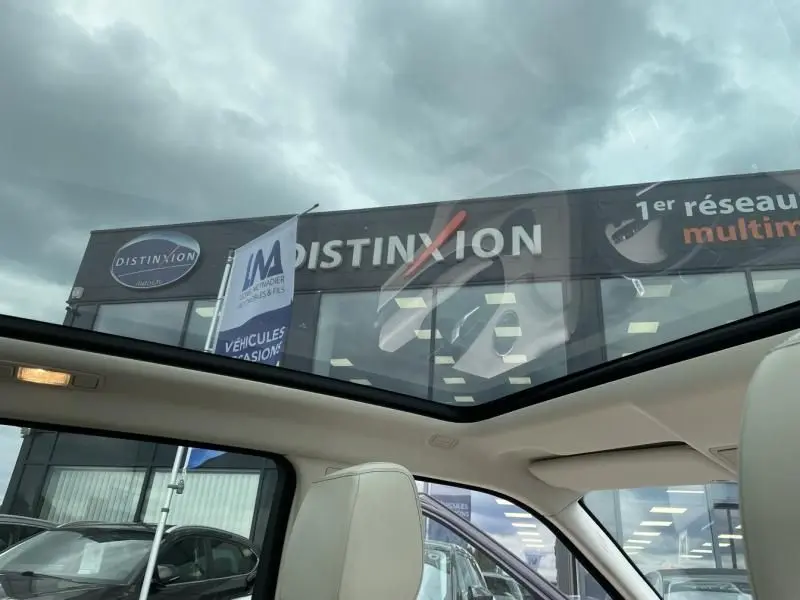 Toit panoramique ouvert montrant l'intérieur clair d'un Range Rover Evoque marron métal, vue depuis l'habitacle vers l'extérieur.