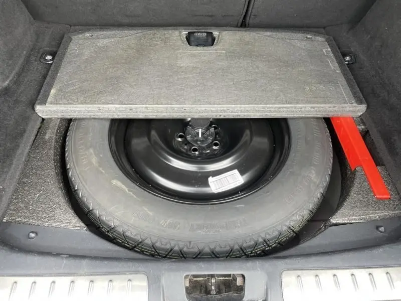 Vue du coffre du Range Rover Evoque 2017 marron métal, montrant la roue de secours sous la trappe ouverte.