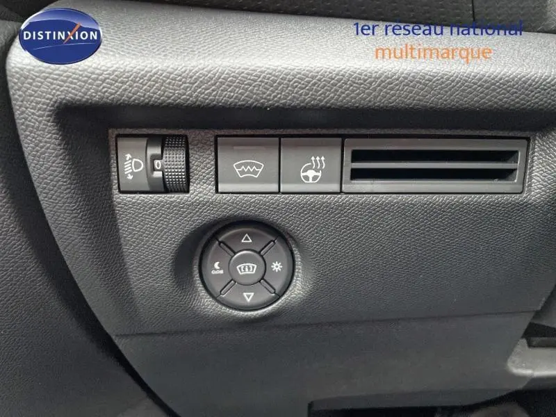 Gros plan sur les commandes de réglage des phares et dégivrage, tableau de bord noir du Citroën C4 gris hybride 2024.