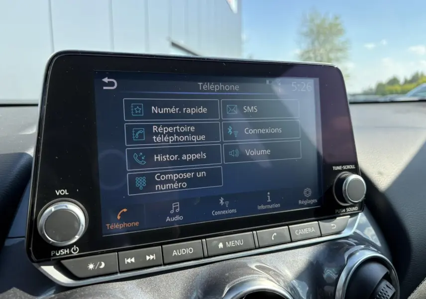 Écran tactile central du Nissan Juke gris Dark Metal 2024 affichant le menu téléphone avec commandes audio et caméra.