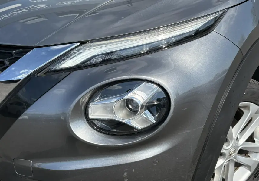 Gros plan sur le phare avant droit du Nissan Juke 2024 gris Dark Metal, mettant en valeur le design LED et la jante alliage 17 pouces.