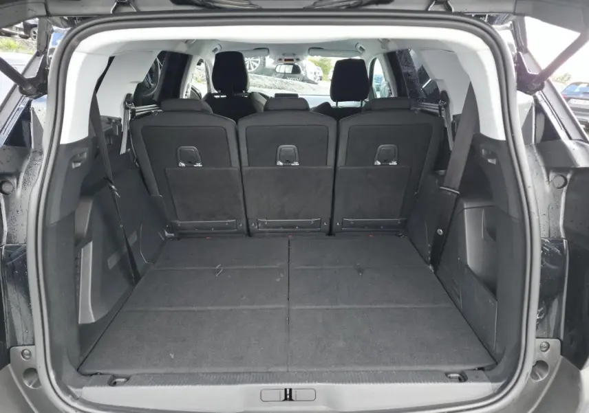 Coffre ouvert d'un Peugeot 5008 noir 2021, vue arrière montrant les sièges arrière relevés et l'espace de chargement.