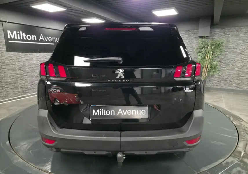 Vue arrière d'un Peugeot 5008 noir 2021 avec attelage, dans un showroom intérieur.