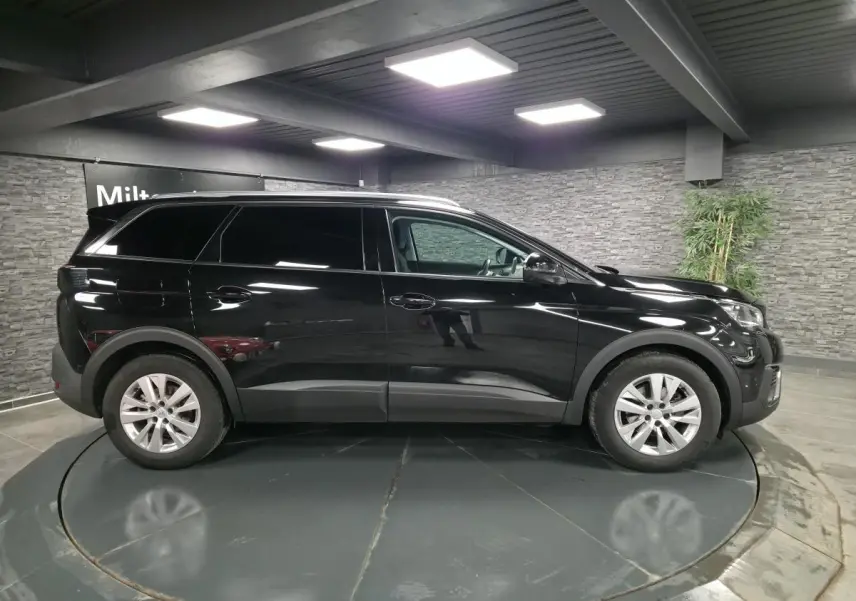 Profil droit d'un Peugeot 5008 noir métallisé 2021, avec jantes alliage 17 pouces et vitres teintées.