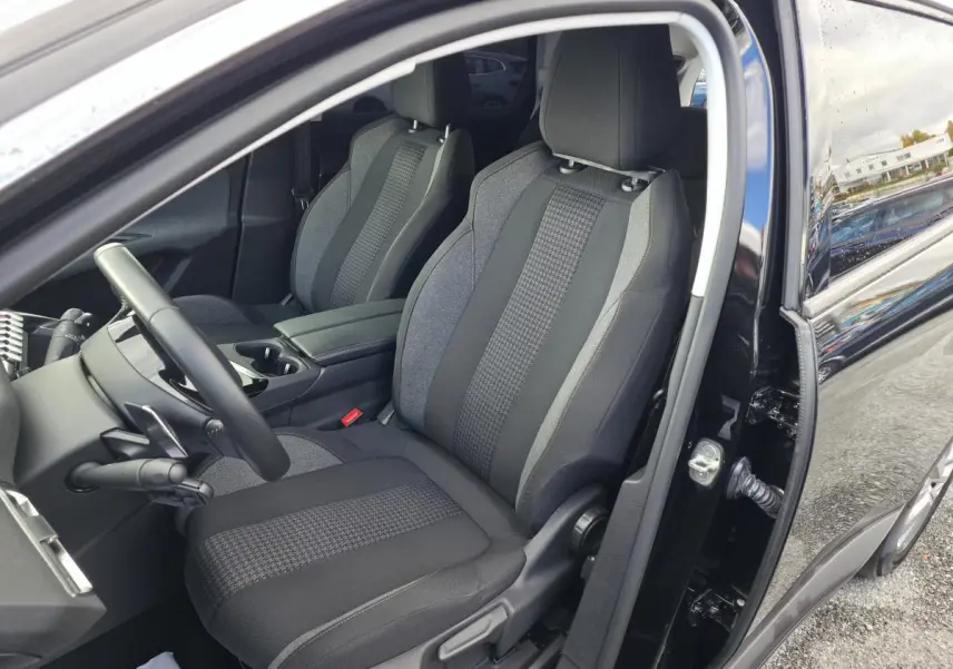Intérieur côté conducteur du Peugeot 5008 noir 2021, sièges textile gris et noir avec console centrale ouverte.