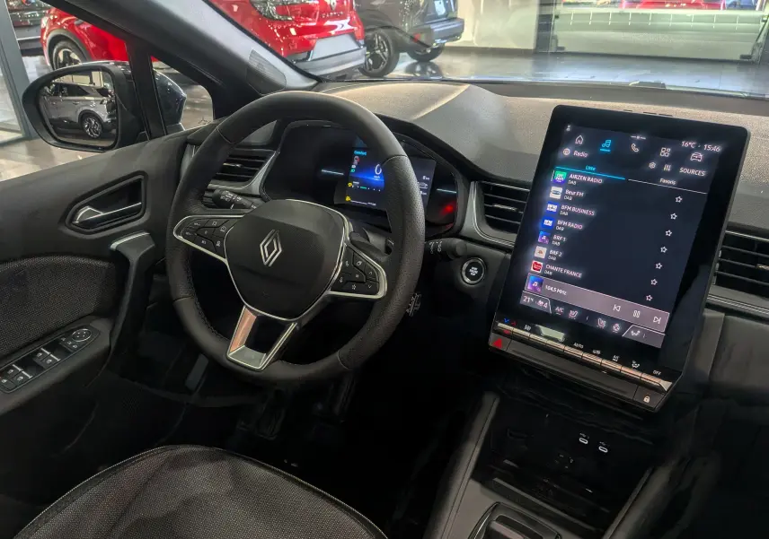 Vue intérieure du poste de conduite du Renault Captur 2025 avec écran tactile vertical et volant multifonction noir.