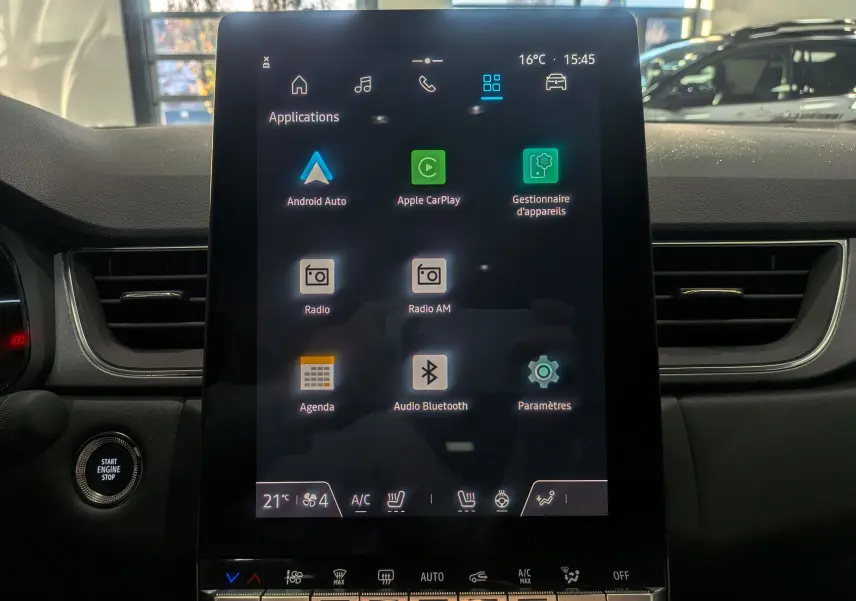 Écran tactile central du tableau de bord du Renault Captur 2025, affichant les applications connectées et commandes climatisation.