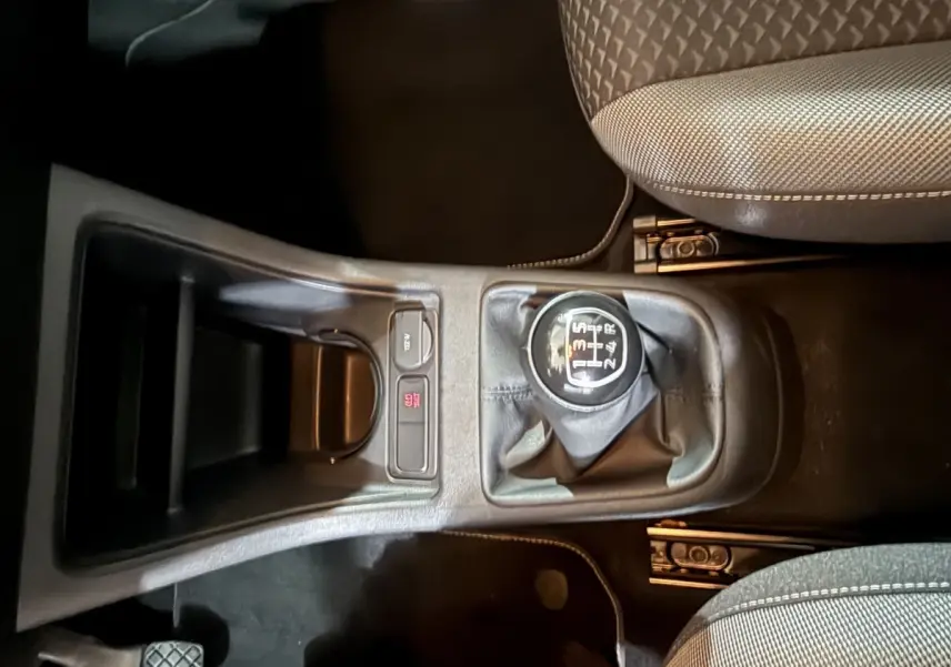 Vue plongeante sur la console centrale du Volkswagen Up 1.0 65 Active gris foncé, mettant en valeur le levier de vitesses manuel et les sièges avant.