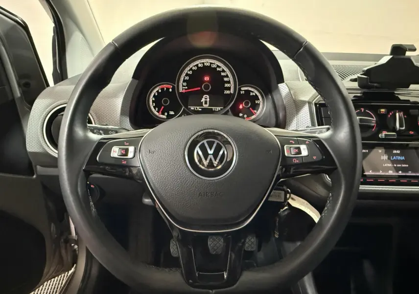 Vue intérieure centrée sur le volant cuir noir du Volkswagen Up 1.0 65 Active avec tableau de bord et commandes visibles.