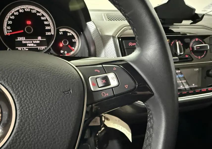 Vue rapprochée de l’intérieur d’un Volkswagen Up 2022, volant cuir avec commandes multifonctions et tableau de bord digital.