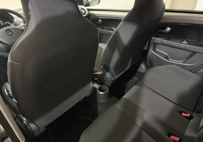 Vue intérieure arrière du Volkswagen Up 1.0 65 Active, sièges noirs et console centrale compacte visible.