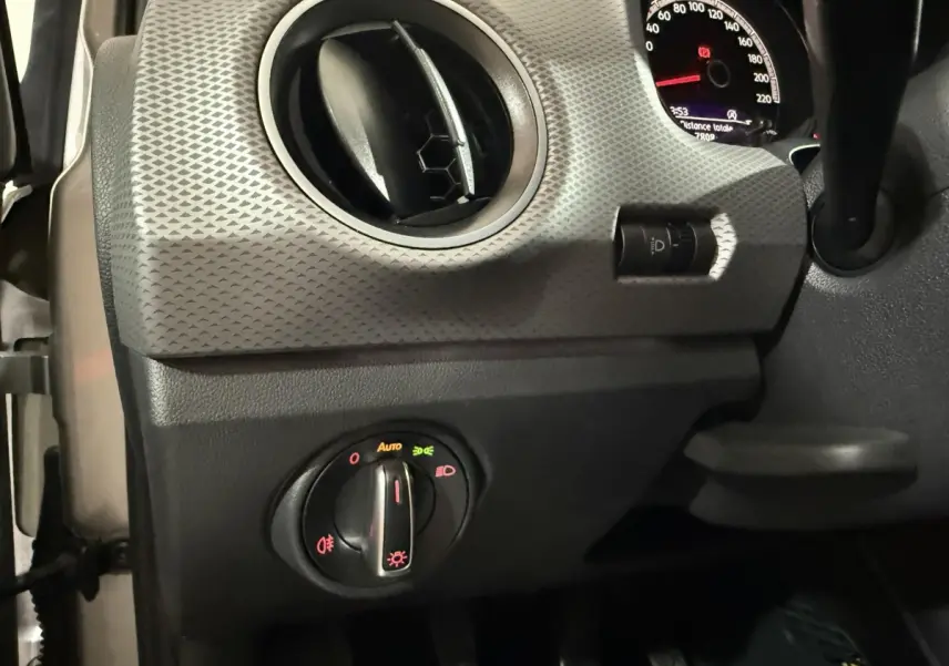 Détail du tableau de bord gris foncé du Volkswagen Up 2022, avec commande des phares et aérateur rond.