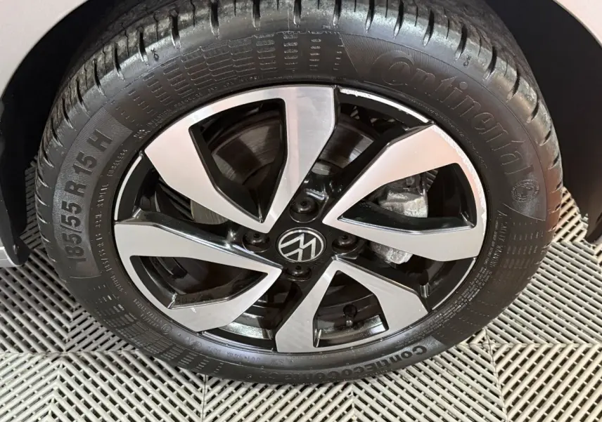 Gros plan sur la jante alliage bicolore noir et argentée d’un Volkswagen Up gris foncé, vue côté roue avant.