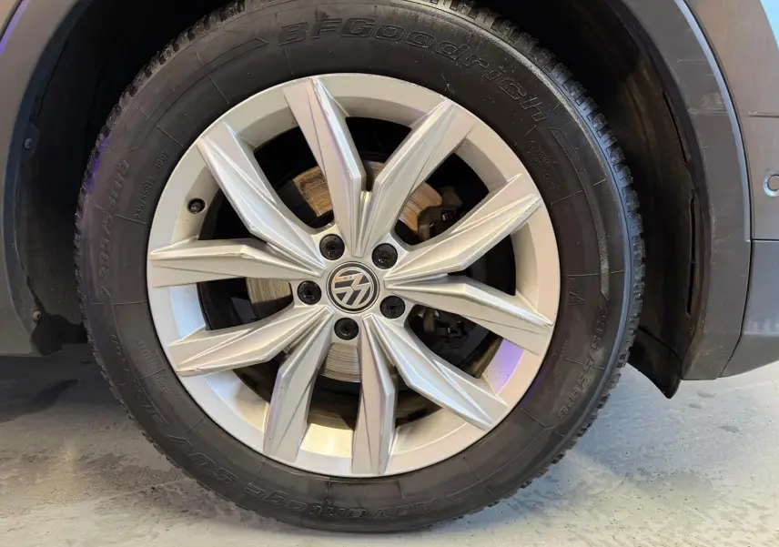 Gros plan sur la jante alu grise avec logo Volkswagen du côté arrière droit du Volkswagen Tiguan gris 2018.