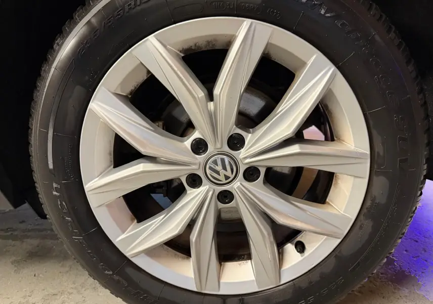 Gros plan sur la jante alu argentée d'un Volkswagen Tiguan gris, mettant en valeur le logo VW central.