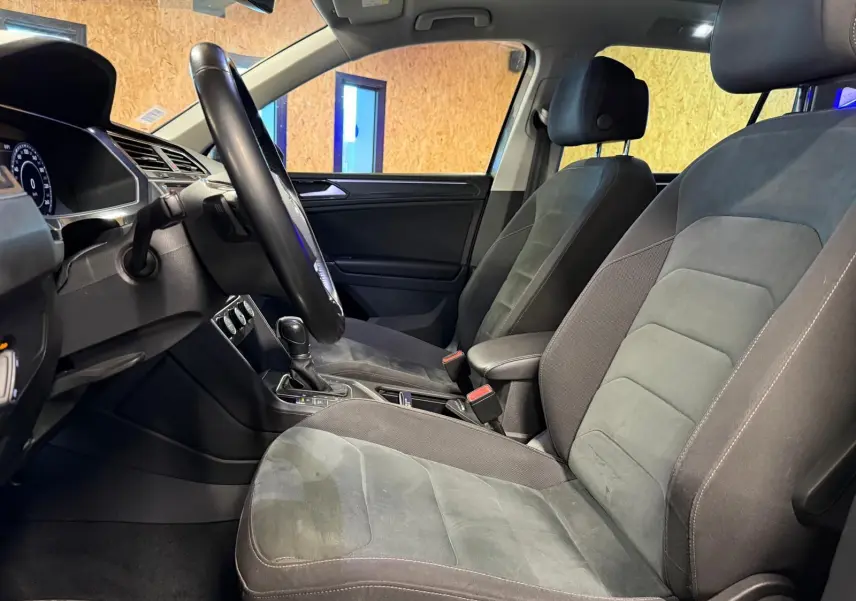 Vue intérieure côté conducteur du Volkswagen Tiguan 2018, sièges sport gris avec volant cuir multifonctions.