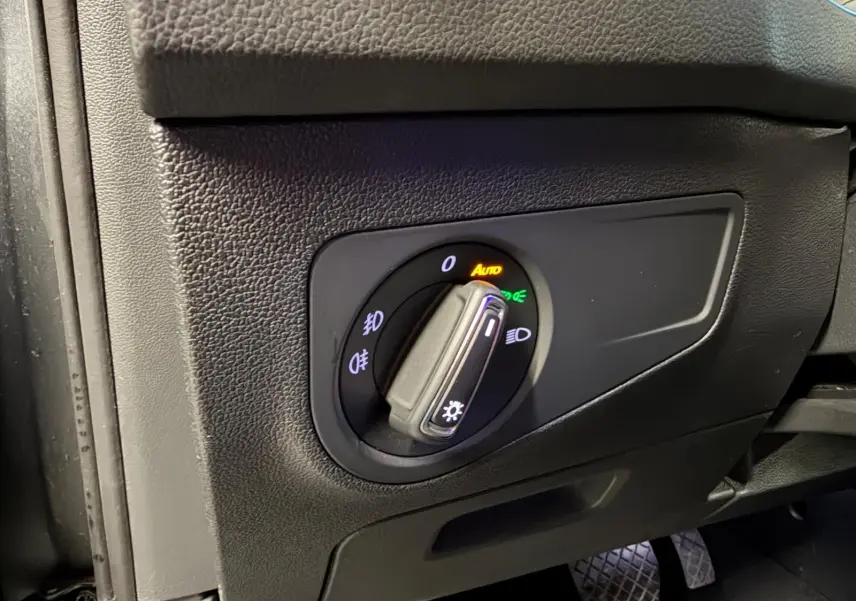 Gros plan sur le bouton de commande des phares dans l'habitacle du Volkswagen Tiguan gris, côté conducteur.