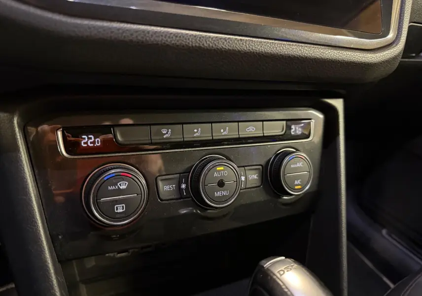Gros plan sur la console centrale du Volkswagen Tiguan gris, montrant les commandes de climatisation automatique et la boîte automatique DSG.