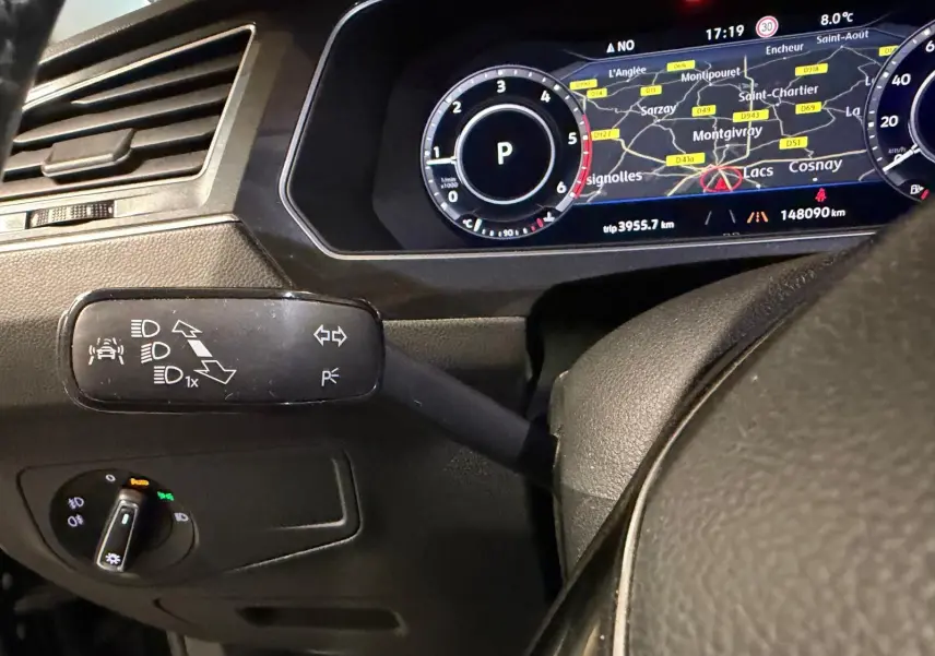 Gros plan sur le combiné d'instruments numérique et la commande des phares du Volkswagen Tiguan gris, tableau de bord moderne.