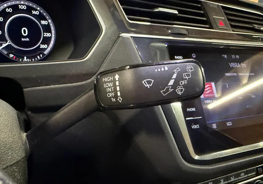 Gros plan sur la commande d'essuie-glace du Volkswagen Tiguan gris, avec tableau de bord numérique et écran tactile visible.