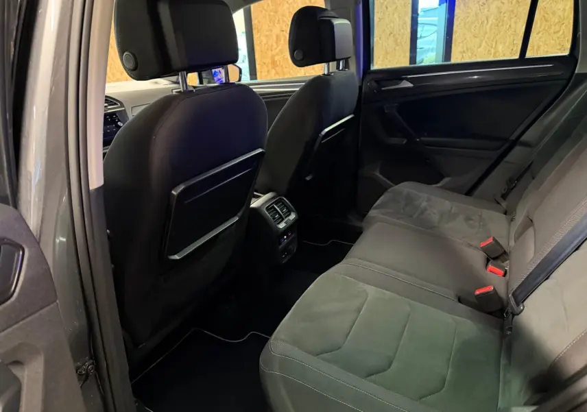 Vue intérieure arrière du Volkswagen Tiguan gris, montrant la banquette arrière en tissu et les dossiers des sièges avant.