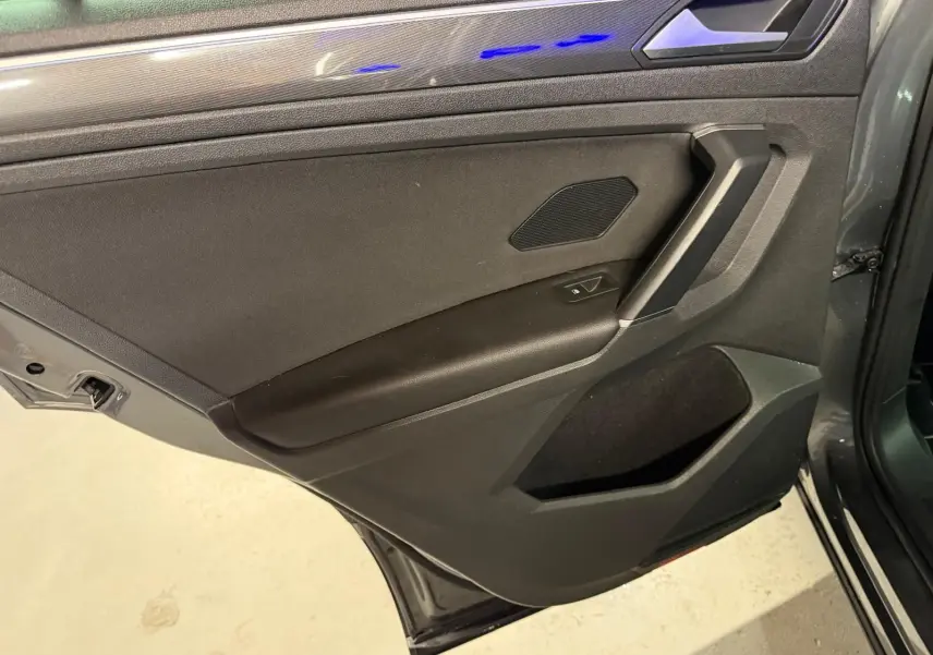 Vue intérieure de la porte arrière droite gris tungstène du Volkswagen Tiguan 2018 avec éclairage d'ambiance bleu.