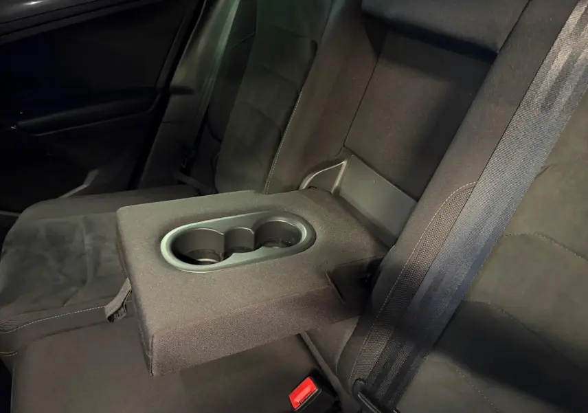 Vue rapprochée de l'accoudoir central arrière avec porte-gobelets du Volkswagen Tiguan gris, banquette arrière en tissu noir.